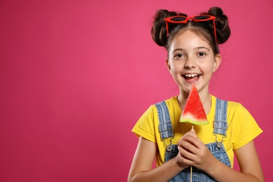 Photo of Cute little girl with watermelon on pink background. Space for text