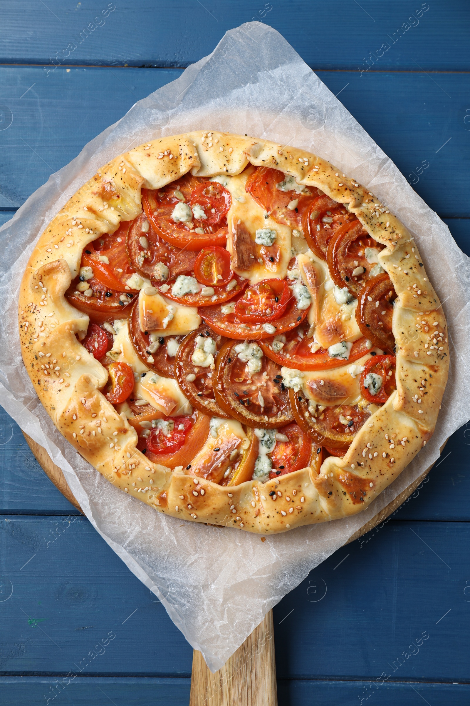 Photo of Tasty galette with tomato and cheese (Caprese galette) on blue wooden table, top view