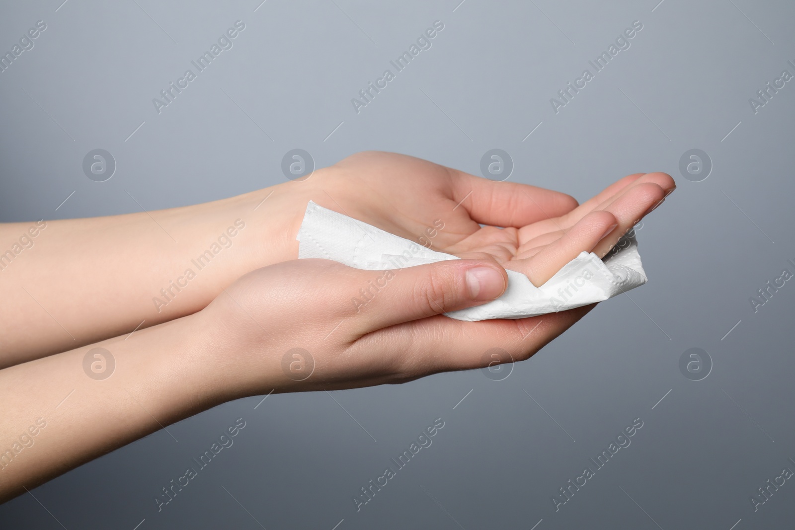 Photo of Woman wiping hands with paper towel on grey background, closeup