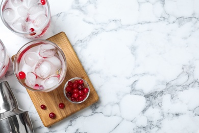 Photo of Flat lay composition of cocktail with vodka, ice and cranberry on white marble table. Space for text