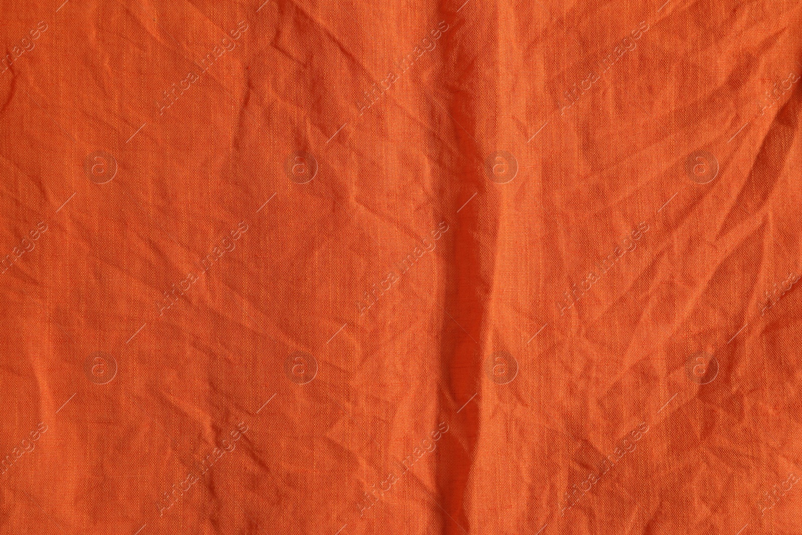 Photo of Crumpled orange fabric as background, top view