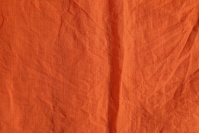 Photo of Crumpled orange fabric as background, top view