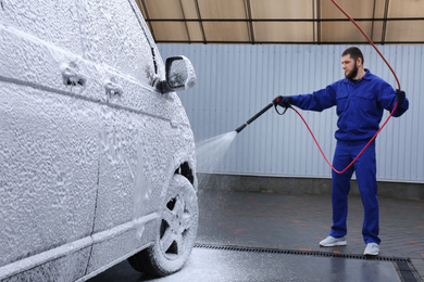 Photo of Worker covering automobile with foam at car wash