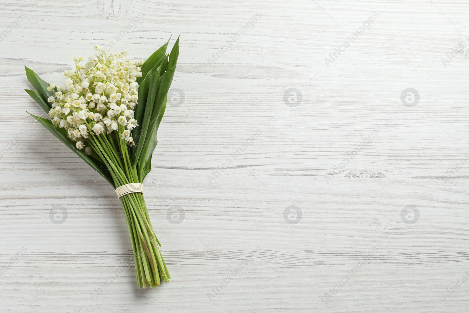 Photo of Beautiful lily of the valley bouquet on white wooden table, top view. Space for text