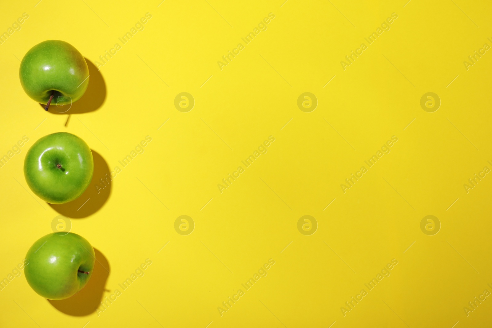Photo of Tasty green apples on yellow background, flat lay. Space for text
