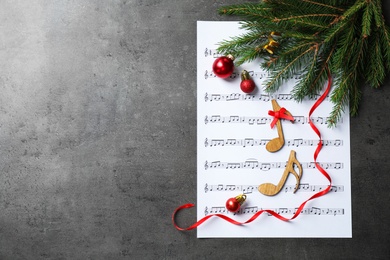 Photo of Christmas decorations, notes and music sheet on grey stone table, flat lay with space for text