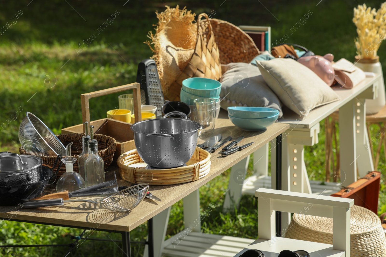 Photo of Small tables with many different items on garage sale outdoors