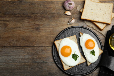 Photo of Tasty fried eggs with bread on wooden table, flat lay. Space for text