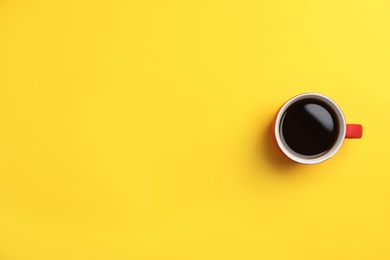 Ceramic cup with hot aromatic coffee on color background, top view