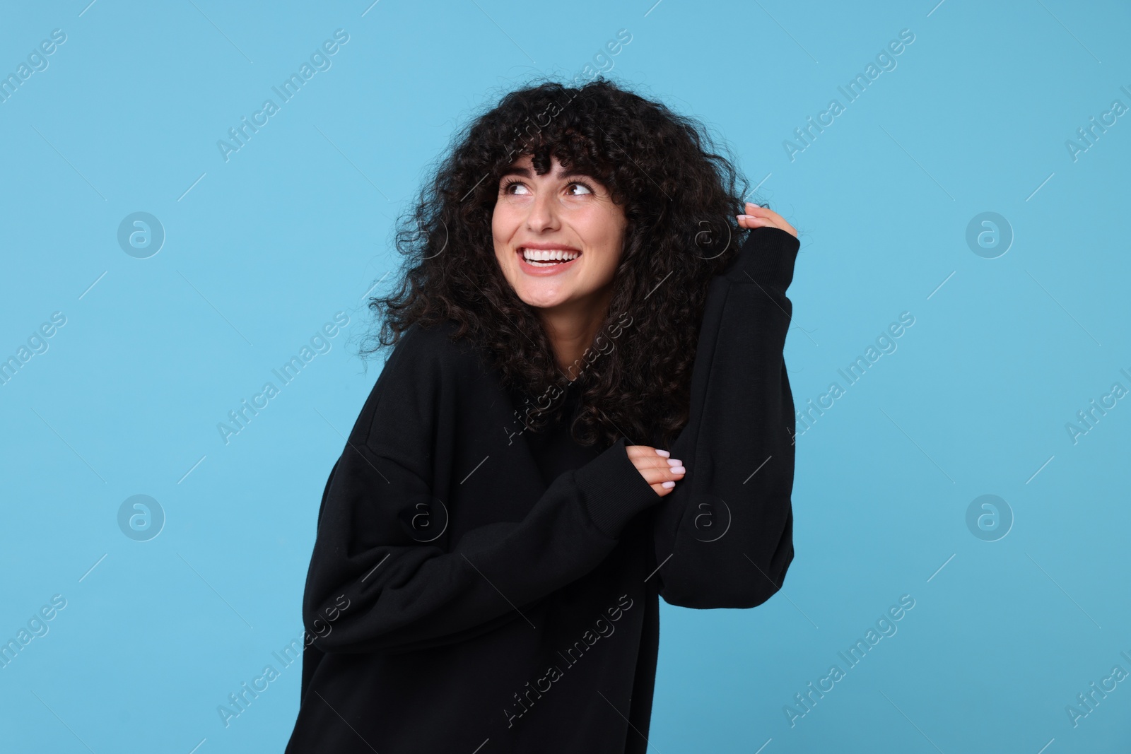 Photo of Happy young woman in stylish black sweater on light blue background