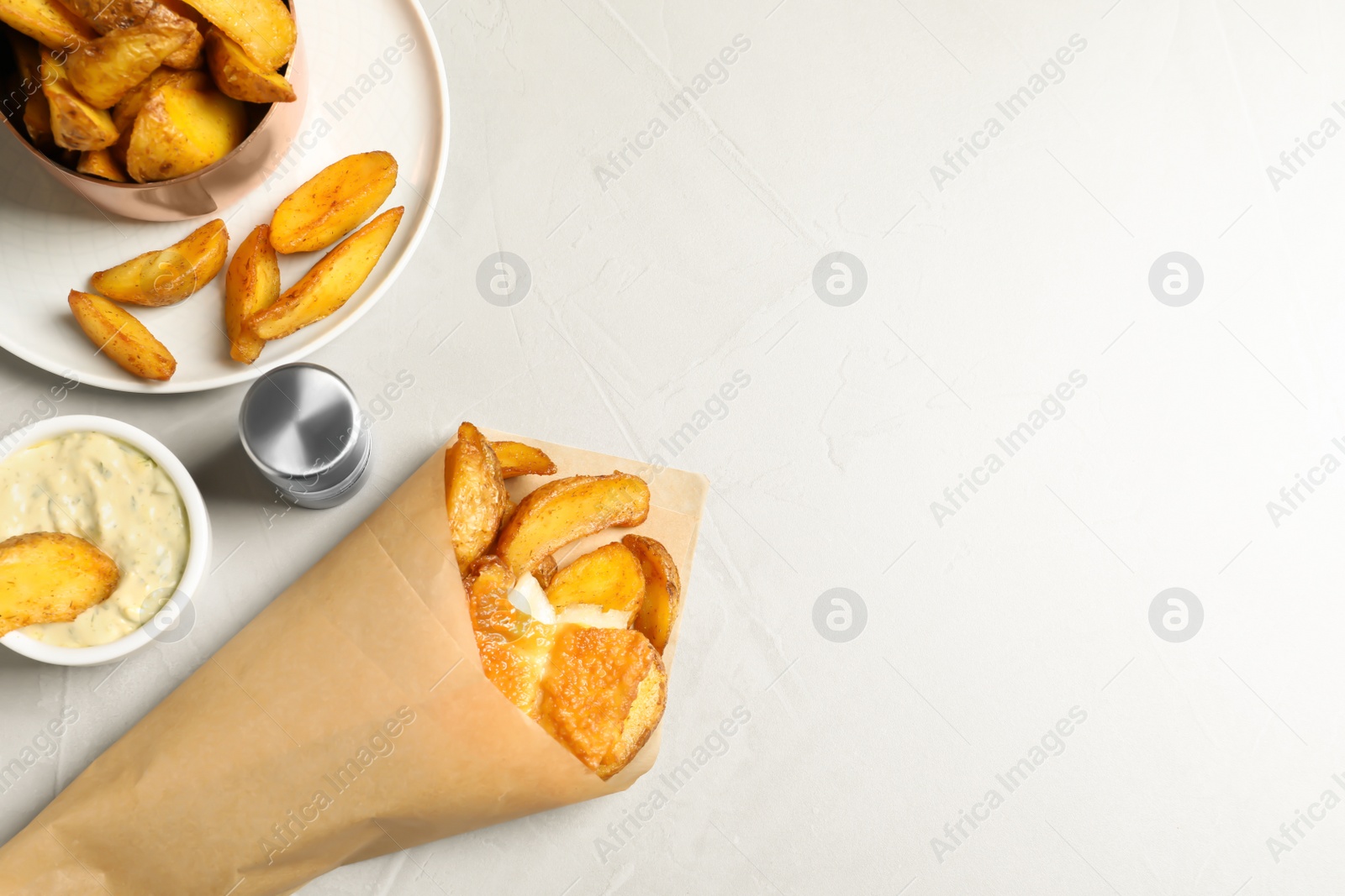 Photo of British traditional fish and potato chips in paper cone on light background, top view with space for text