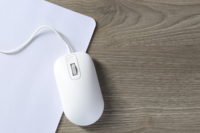 Wired mouse and mousepad on wooden table, top view. Space for text