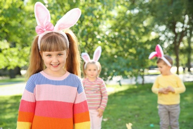 Cute little girl with bunny ears in park. Easter celebration