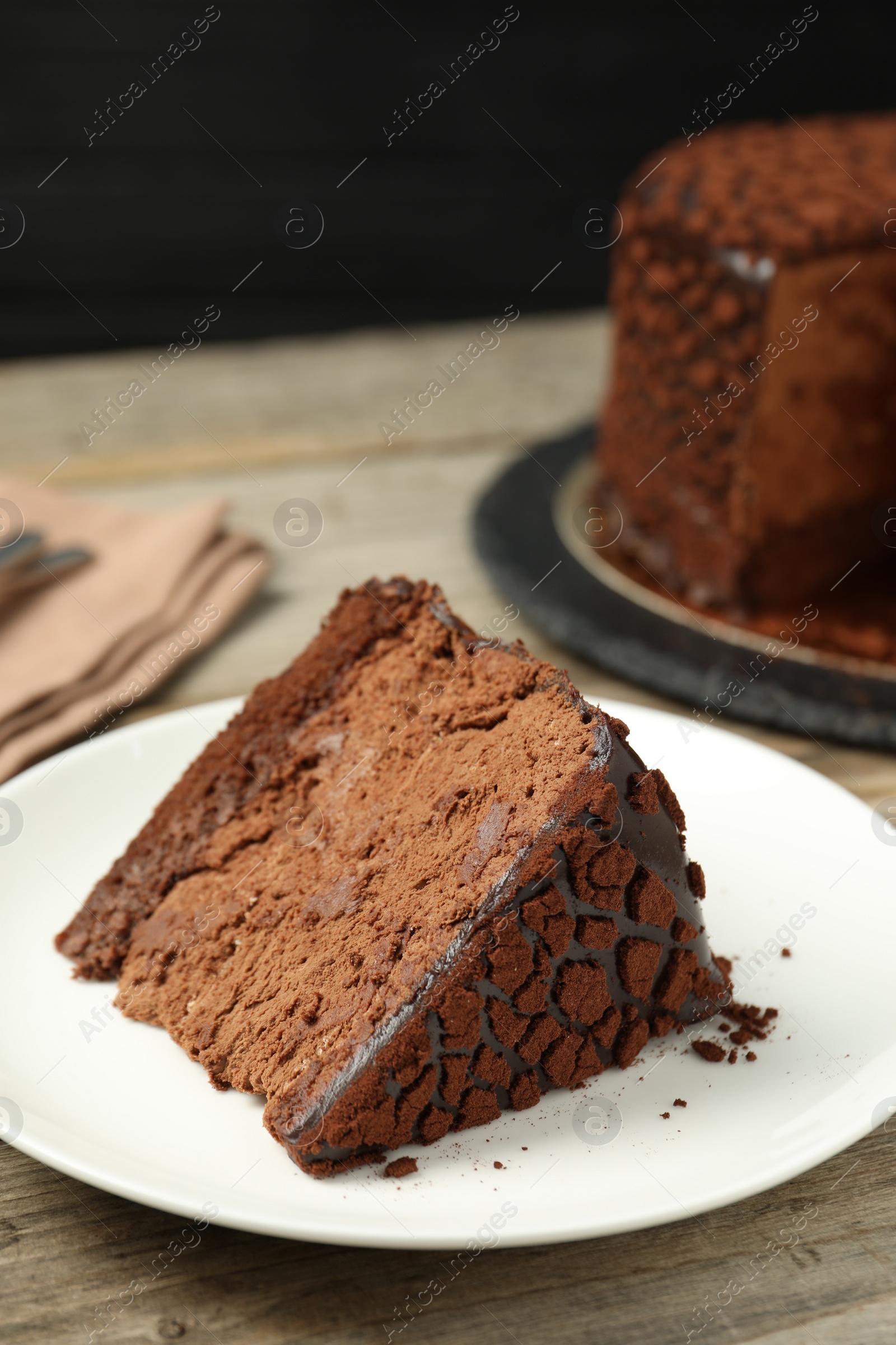 Photo of Piece of delicious chocolate truffle cake on wooden table