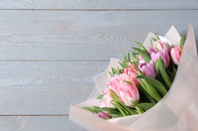 Bouquet of beautiful tulips on grey wooden table, top view. Space for text