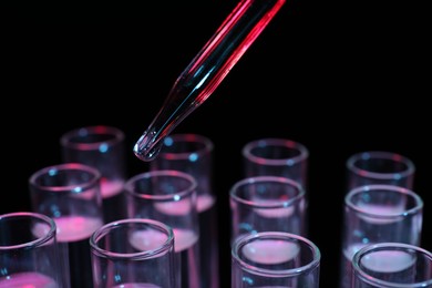 Photo of Dripping reagent into test tube on black background, closeup. Laboratory analysis