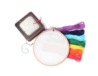 Colorful threads and different embroidery accessories on white background, top view