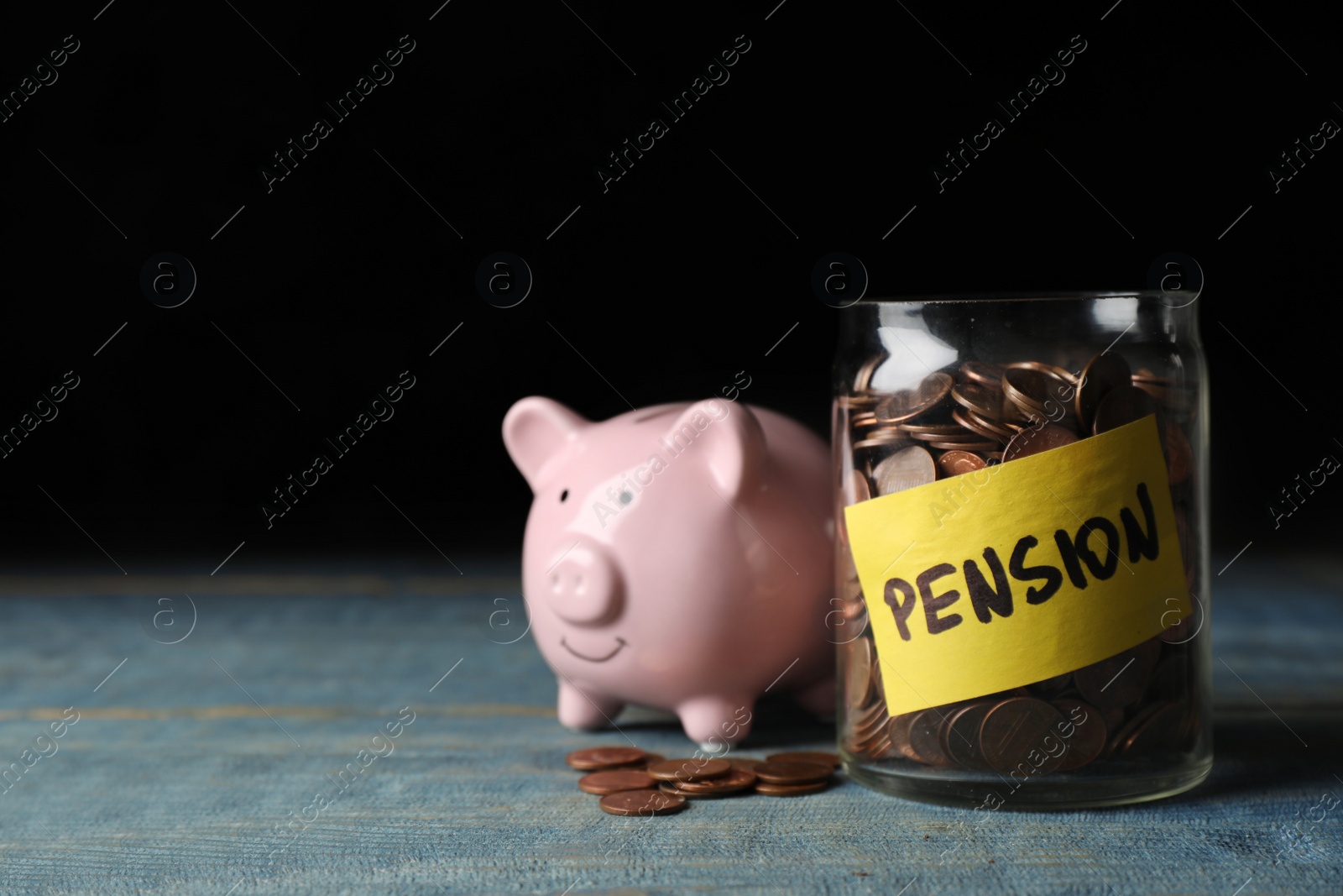 Photo of Piggy bank and jar of coins with word PENSION on table. Space for text