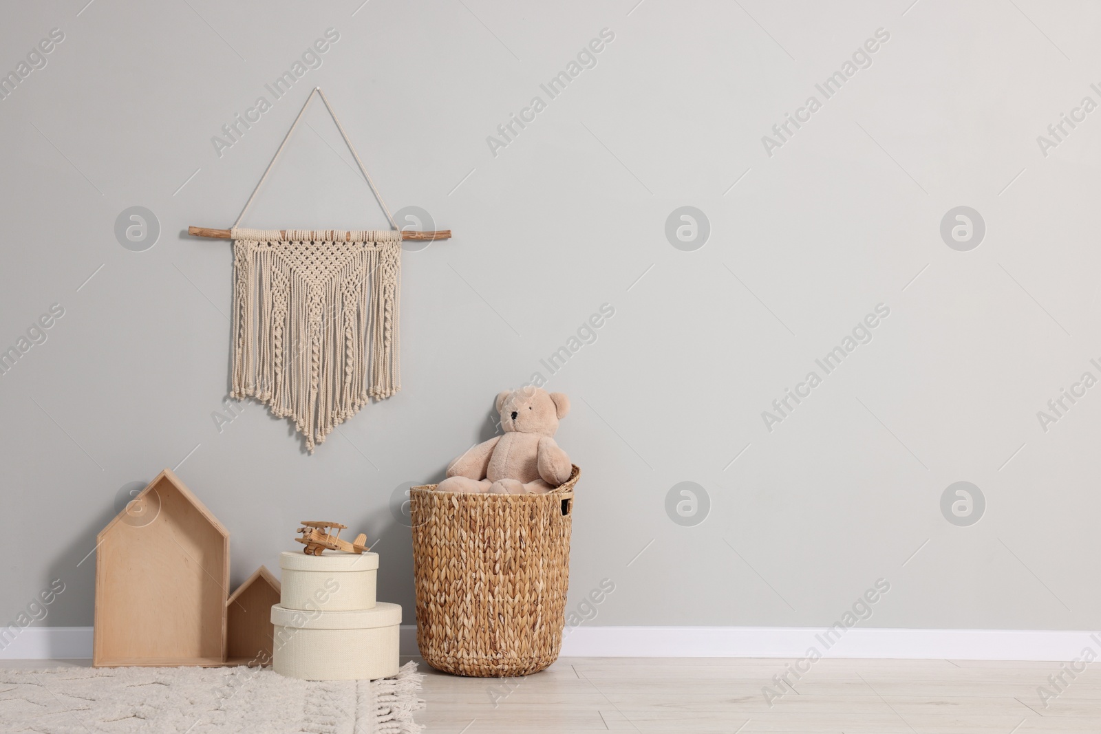 Photo of Beautiful children's room with grey wall, decor elements and toys, space for text. Interior design