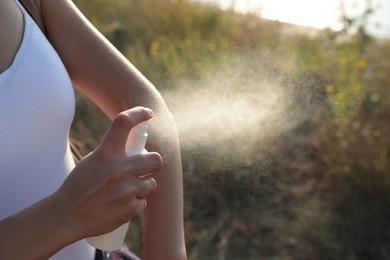 Photo of Woman applying insect repellent onto arm outdoors, closeup. Space for text