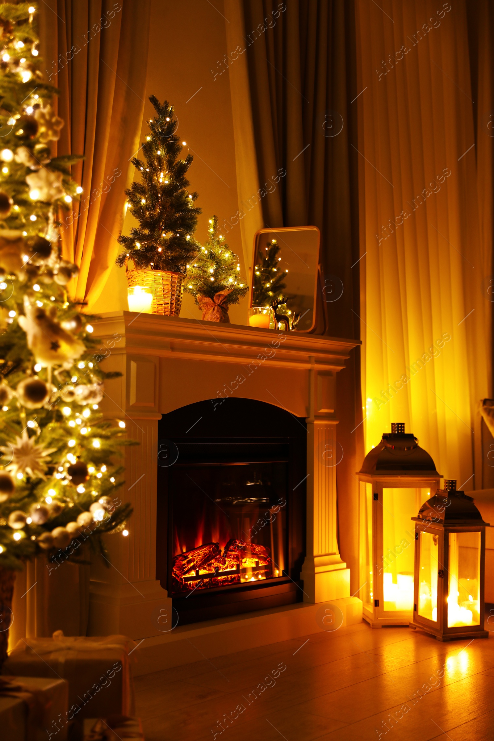 Photo of Beautiful fireplace, Christmas tree and other decorations in living room at night. Interior design