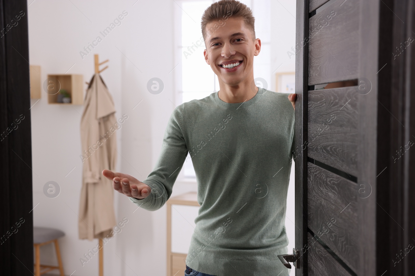 Photo of Happy man welcoming near door. Invitation to come indoors