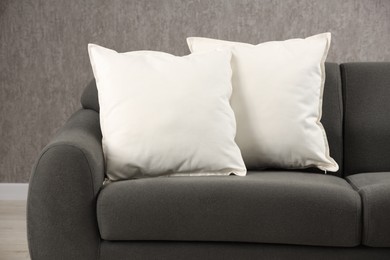 Photo of Two soft white pillows on sofa indoors