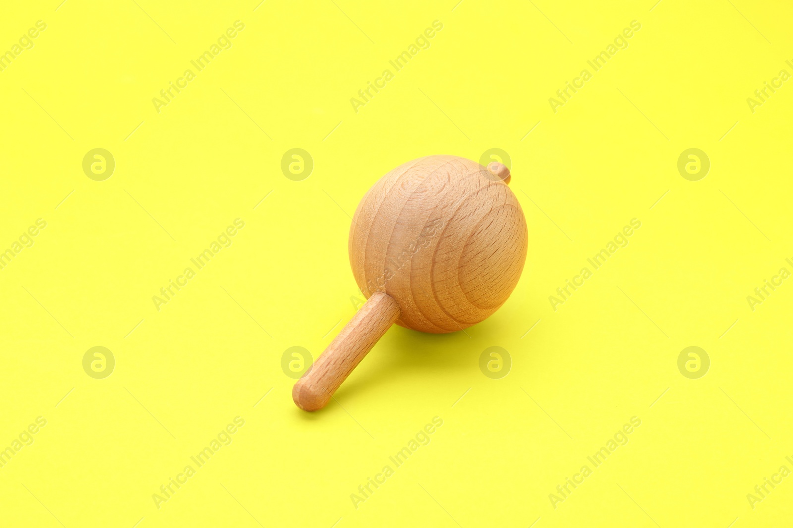 Photo of One wooden spinning top on yellow background. Toy whirligig