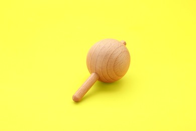 Photo of One wooden spinning top on yellow background. Toy whirligig