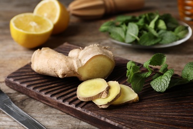 Photo of Board with mint and ginger on wooden table. Cough remedies
