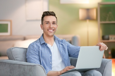 Photo of Young man using laptop at home