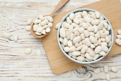 Photo of Uncooked white beans on wooden table, flat lay