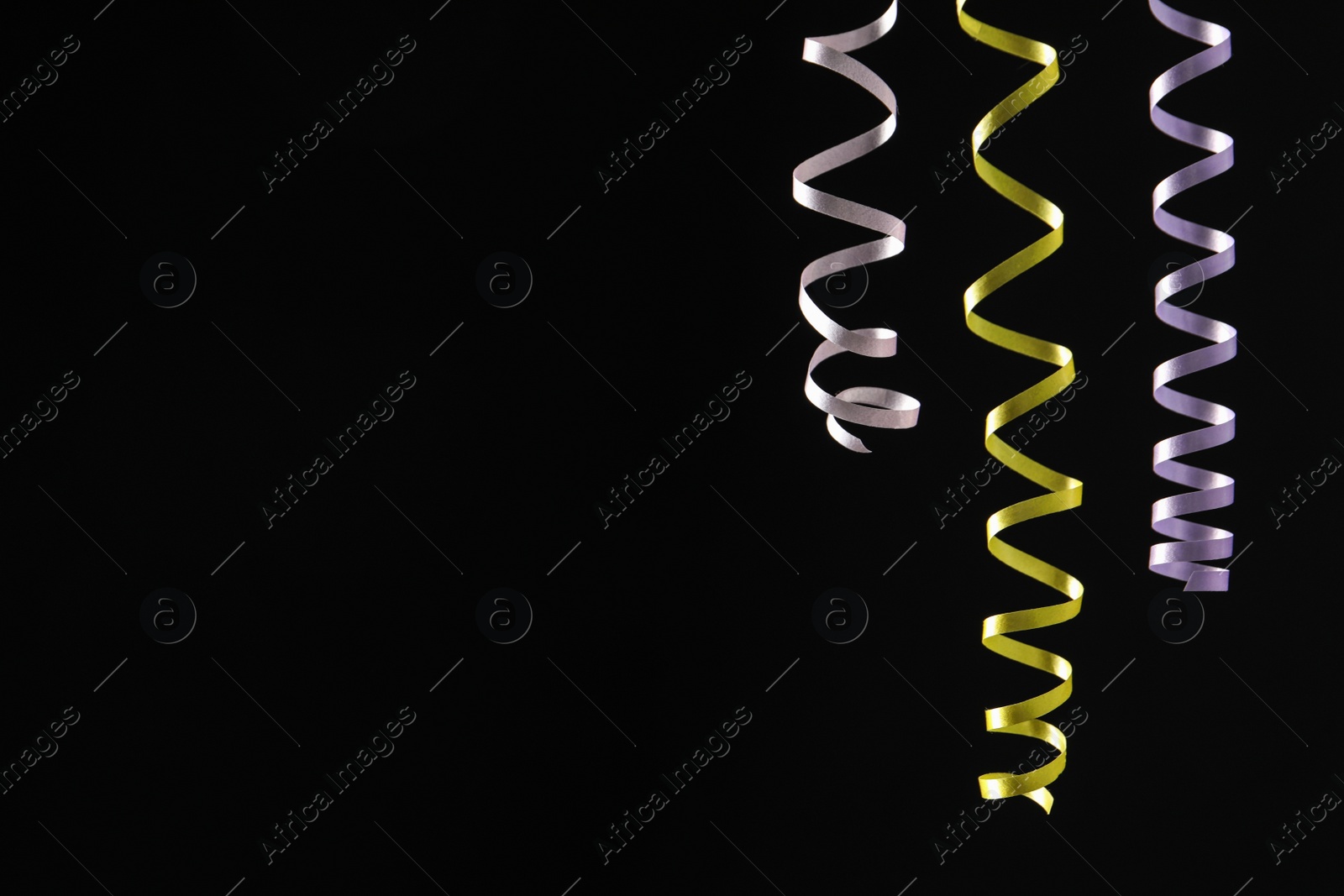 Photo of Colorful serpentine streamers on black background. Space for text