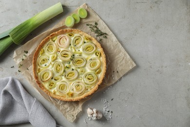 Photo of Tasty leek pie and products on grey textured table, flat lay. Space for text