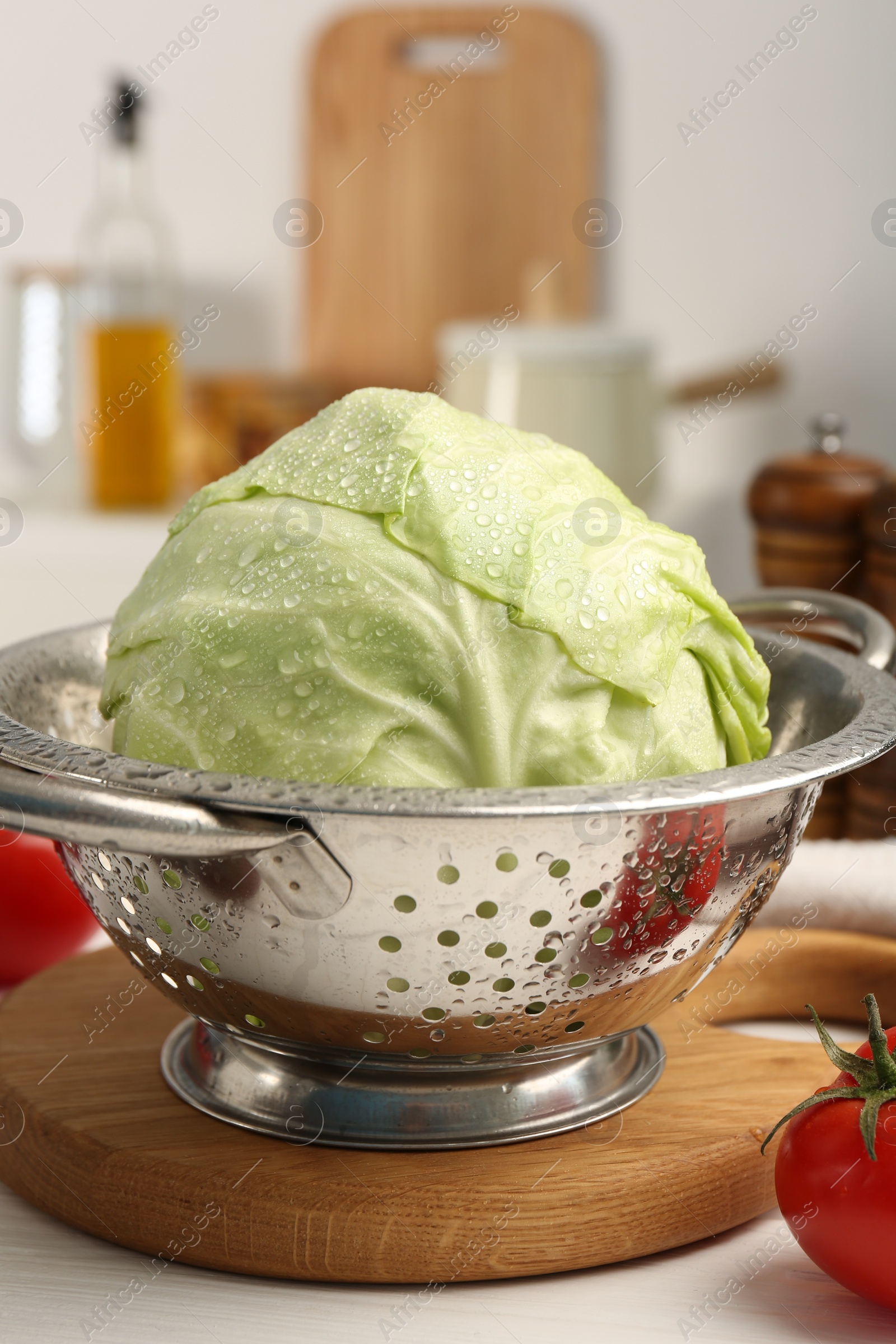 Photo of Wet cabbage in colander on white wooden table, closeup