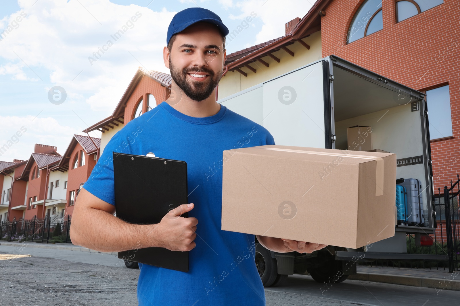 Image of Happy courier with parcel and clipboard outdoors