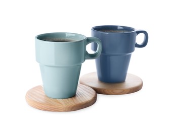 Mugs of coffee and stylish wooden cup coasters on white background