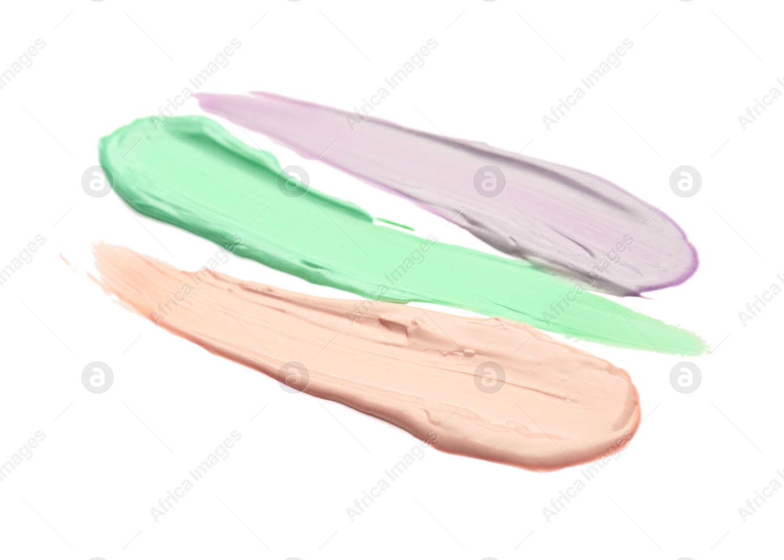 Photo of Strokes of pink, green and purple color correcting concealers isolated on white