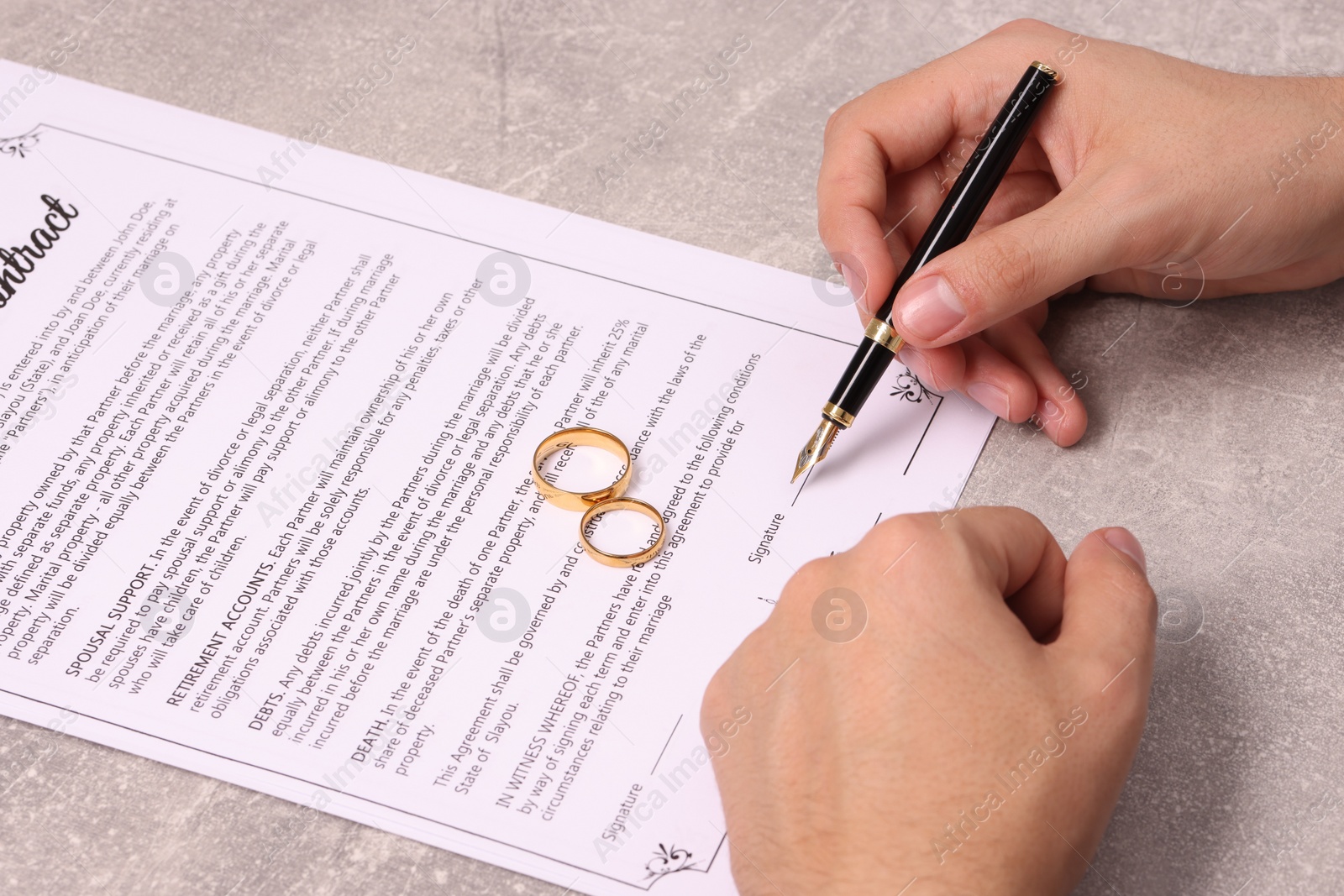 Photo of Man signing marriage contract at light grey table, closeup