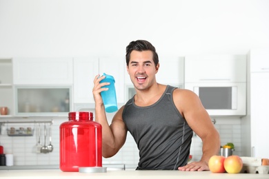Photo of Young athletic man with ingredients for protein shake in kitchen