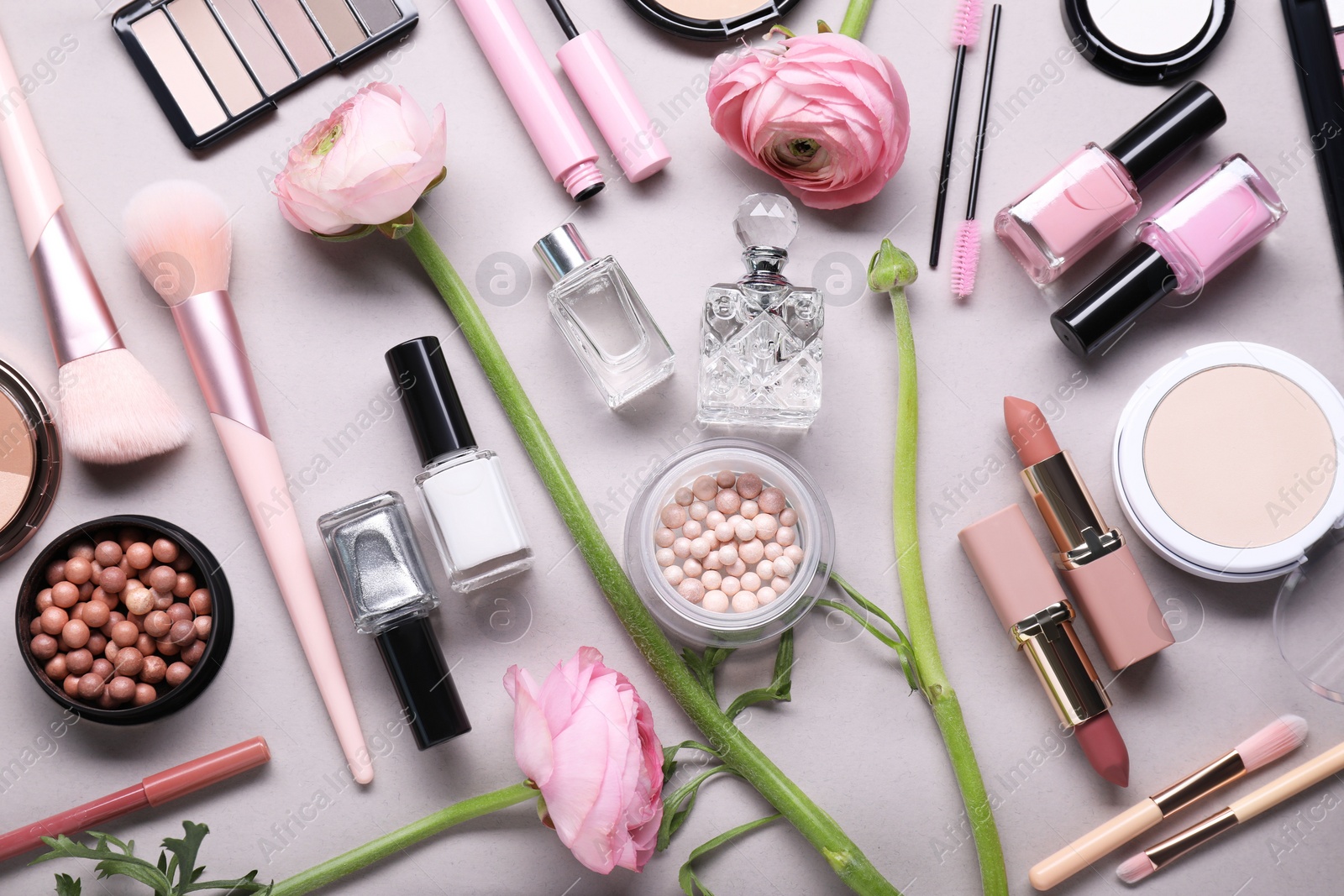 Photo of Flat lay composition with different makeup products and beautiful spring flowers on gray background