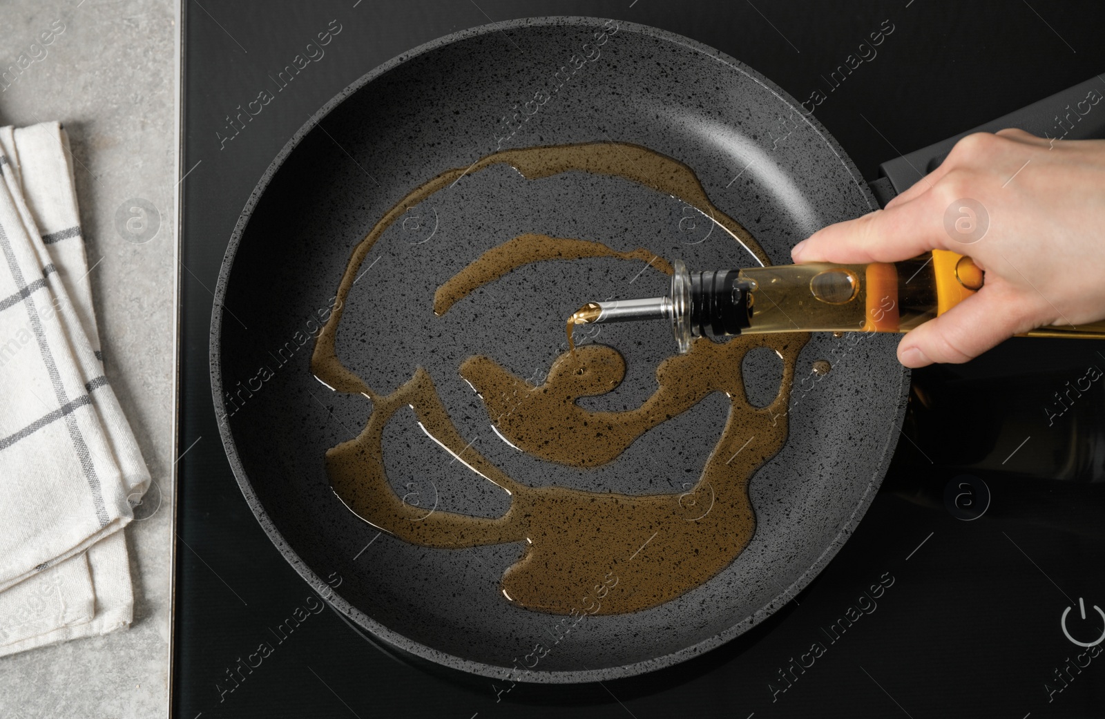 Photo of Woman pouring cooking oil from bottle into frying pan, top view