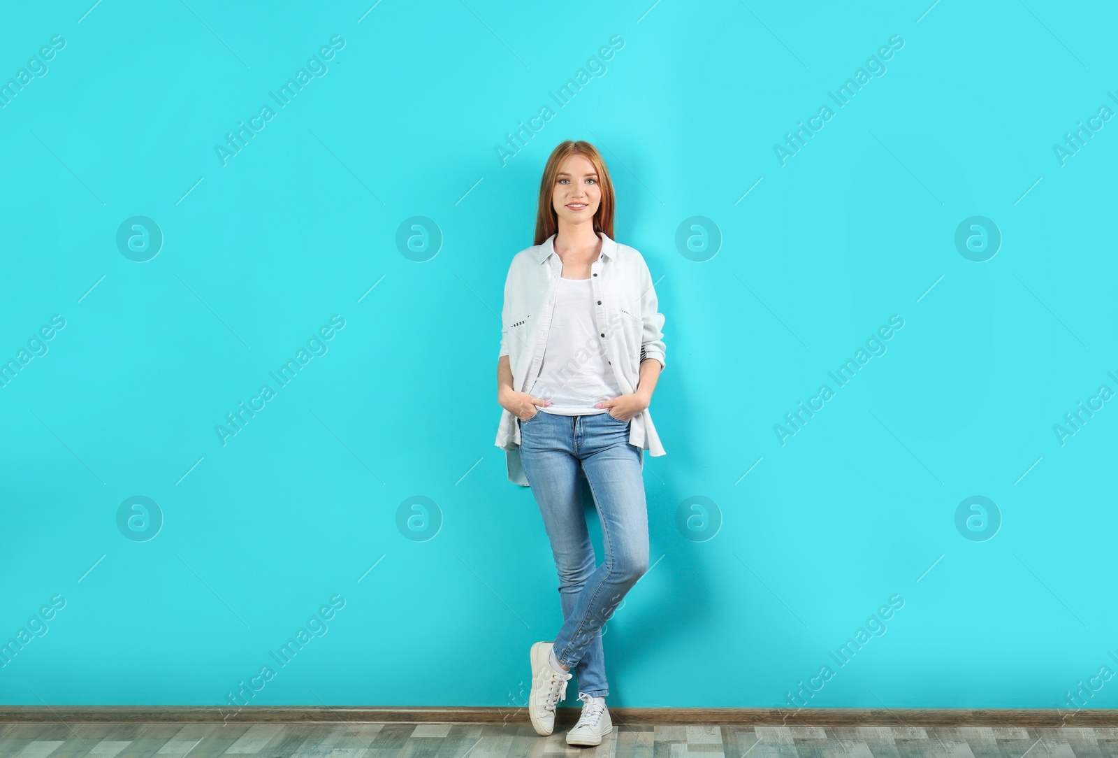 Photo of Young woman in stylish jeans near color wall