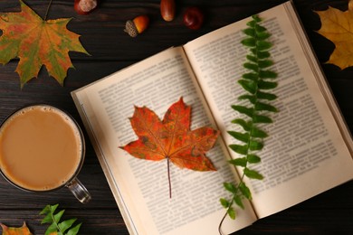Photo of Flat lay composition of book with leaves as bookmark on wooden table