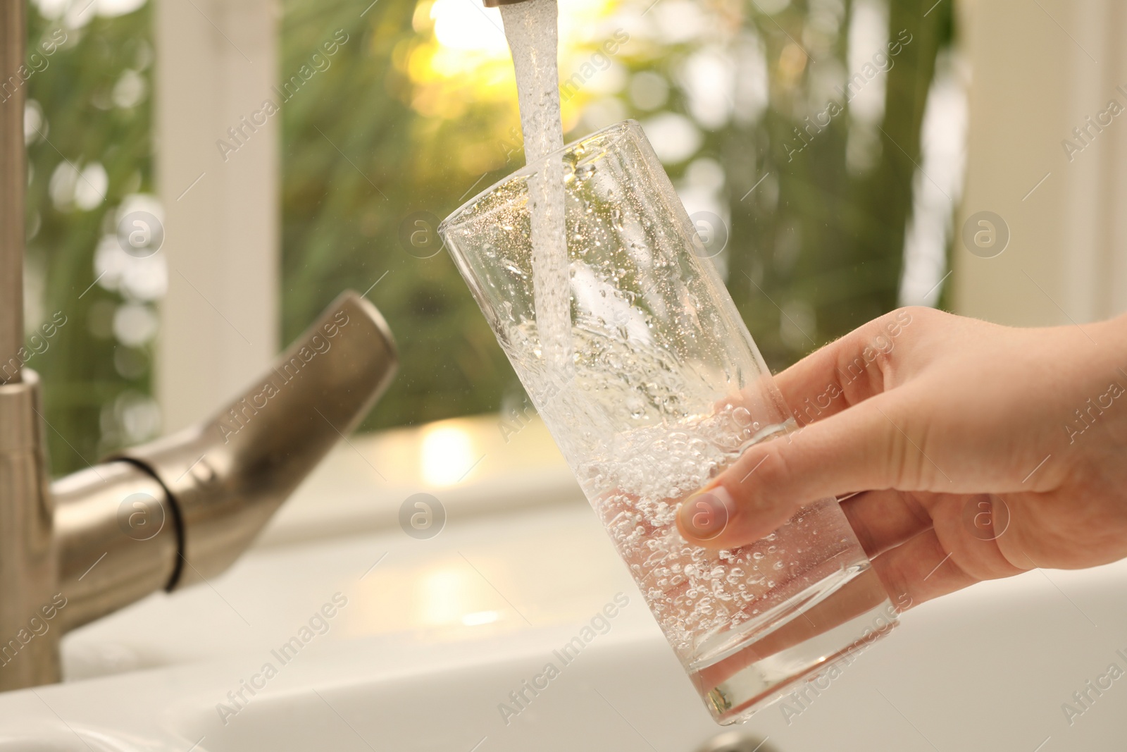 Photo of Woman filling glass with water from tap at home, closeup