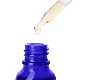 Essential oil dripping from pipette into glass bottle on white background