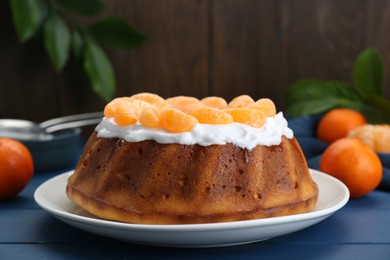 Photo of Homemade yogurt cake with tangerines and cream on blue wooden table