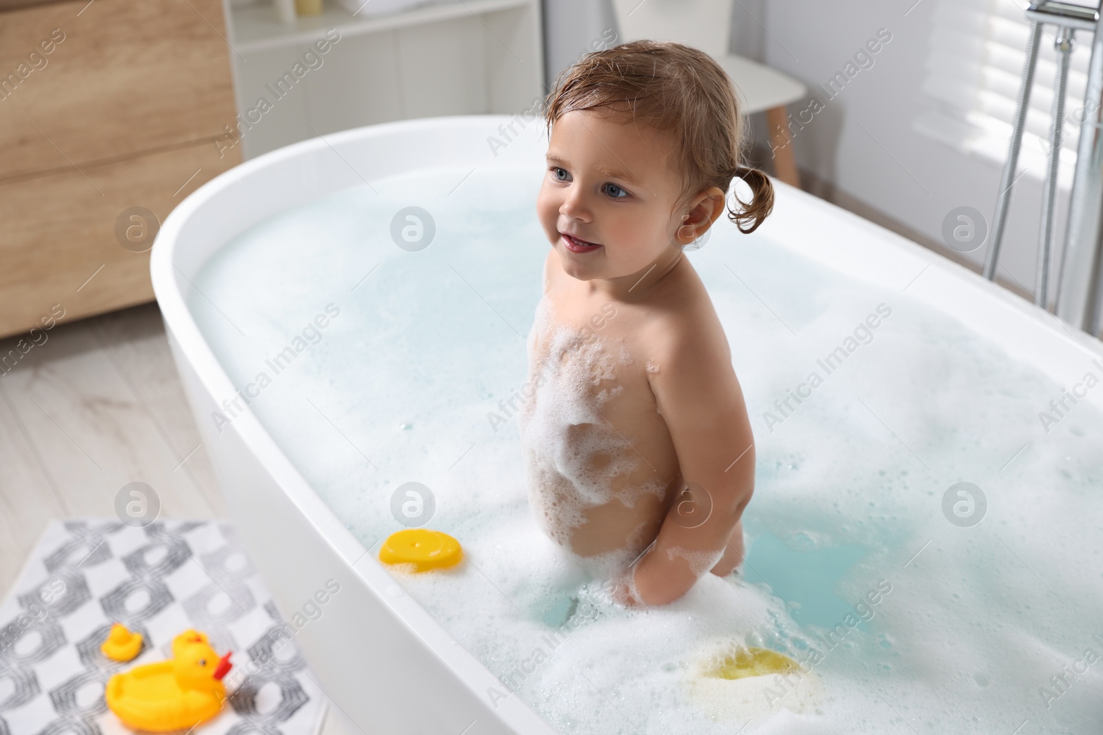 Photo of Cute little girl in foamy bath at home