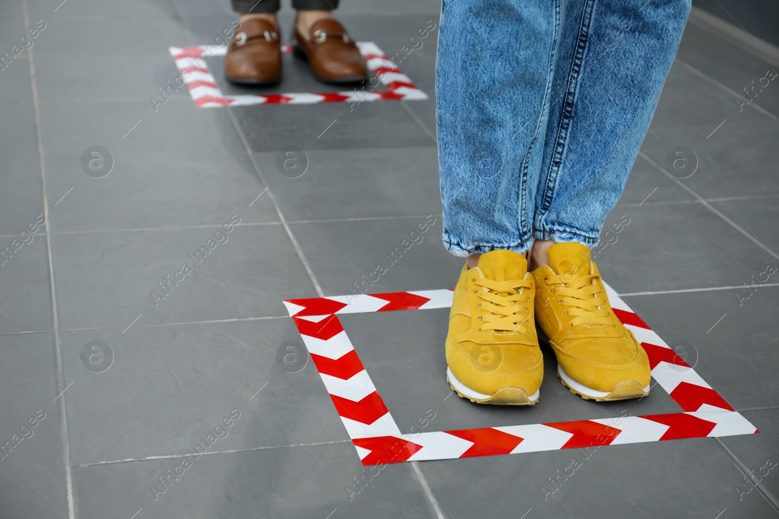 Photo of People standing on taped floor markings for social distance, closeup. Coronavirus pandemic