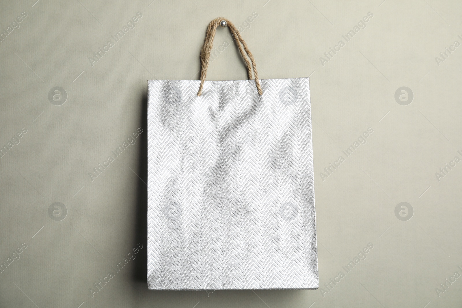 Photo of Silver shopping paper bag on grey background